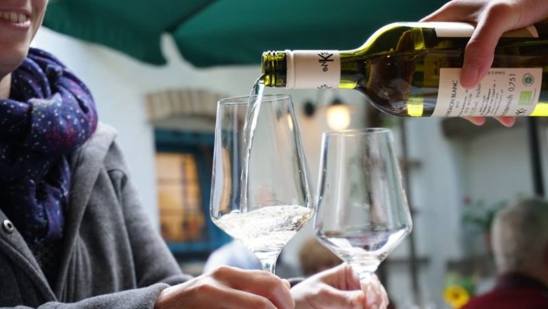 Verkostung, © Bio-Weinbau Killmeyer Wein wird in ein Glas gegossen, während eine Person es hält.