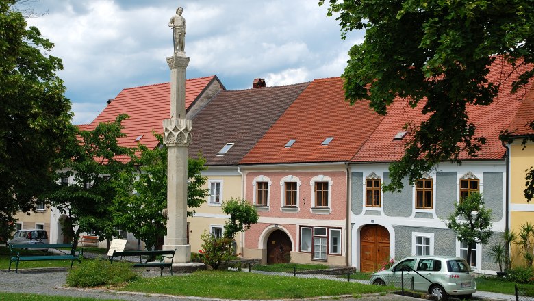 Drosendorf, © Waldviertel Tourismus, Reinhard Mandl Statue auf einer Säule vor bunten Häusern in Drosendorf.