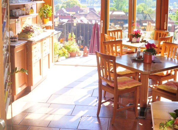 Turm Wachau, © Turm Wachau Innenraum eines sonnigen Wintergartens mit Holzmöbeln und Blick auf eine Landschaft.