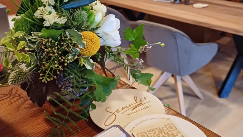 Winzerhof Semmler, © Winzerhof Semmler Ein Blumenarrangement auf einem Tisch im Winzerhof Semmler mit QR-Code und Visitenkarten.