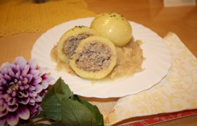 Waldviertler Fleischknödel, © Gasthaus Laister Ein Teller mit Waldviertler Fleischknödeln auf Sauerkraut, dekoriert mit einer Blume.
