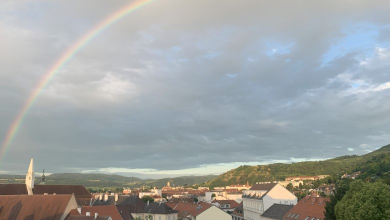 Ausblick auf Krems und Stein, © kremsoase Stadtansicht von Krems mit Regenbogen am Himmel.