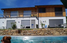 e2 Privatzimmer, © Fam. Exenberger Modernes zweistöckiges Haus mit Holzverkleidung und Pool im Vordergrund.