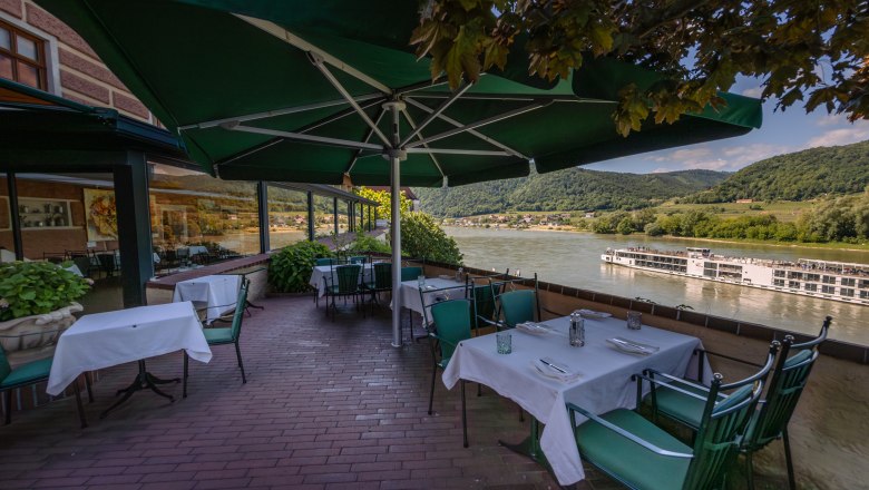 Hotel Schloss Dürnstein, © Niederösterreich Werbung / Maximilian Pawlikowsky Terrasse des Hotel Schloss Dürnstein mit Blick auf die Donau und ein vorbeifahrendes Schiff.