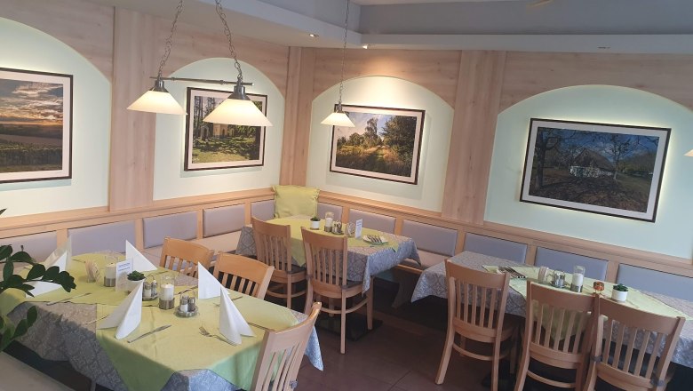 Restaurant Lebenszeit, © Familie Eissler Innenansicht eines Restaurants mit Holzmöbeln und dekorativen Bildern an der Wand.