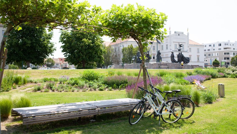 TDR- Hotelleihräder, © Best Western Hotel Zwei Fahrräder stehen an der grünen Donaulände im Hintergrund ersichtlich ist das Rathaus
