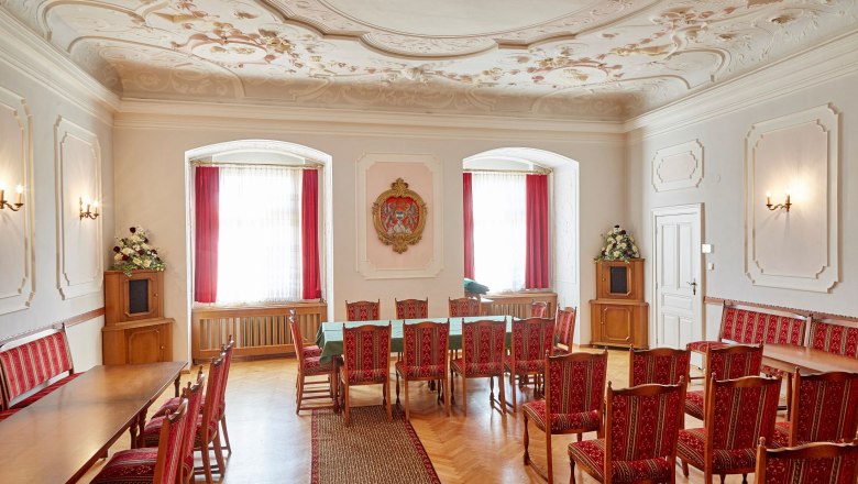 Schloss Groß-Siegharts, © Waldviertel Tourismus, lichtstark.com Ein eleganter Raum im Schloss Groß Siegharts mit roten Stühlen, einem langen Tisch und dekorativer Decke.