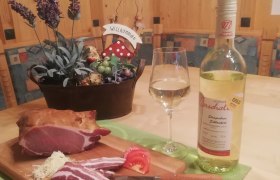 Heurigen, © Heurigenhof Marschall Ein Tisch mit Schinken, Wein und Dekoration.