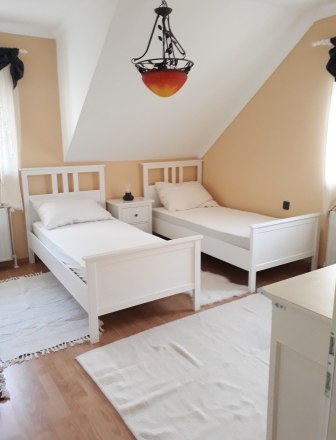 Schlafzimmer mit getrennten Betten, © bed and pool Schlafzimmer mit zwei weißen Einzelbetten und einem Nachttisch dazwischen.