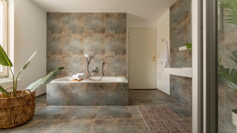 Badezimmer, © Guestia GmbH Modernes Badezimmer mit Badewanne, Pflanzen und Handtuch.