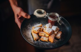 Kaiserschmarren mit Zwetschkenröster, © Niederösterreich Werbung/Daniela Führer Ein Teller mit Kaiserschmarren, bestäubt mit Puderzucker, und einem Glas Zwetschkenröster.