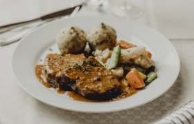 Alm-Ochensbraten, Speckrahmsafterl, Rosengemüse & Semmelknödel, © Niederösterreich Werbung/Sophie Menegaldo Ein Teller mit Ochsenbraten, Speckrahmsauce, Gemüse und Semmelknödeln.