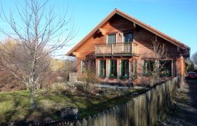 Gästehaus Fries, © Daniel Fries Holzhaus mit Balkon und Garten, umgeben von einem Holzzaun.