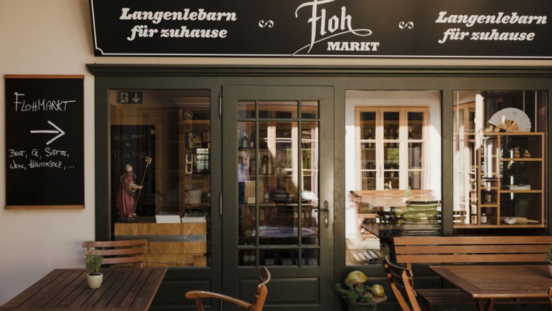 Wirtshaus mit regionalem Flohmarkt, © Niederösterreich Werbung/Michael Reidinger Eingang zu einem regionalen Laden mit Schildern, Holztischen und Stühlen.