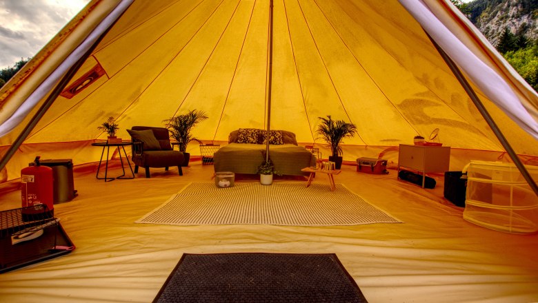 Glamping - Wildnis Zentrum Nasswald, © Jonathan Clark Innenansicht eines luxuriösen Glamping-Zeltes mit Bett, Pflanzen und Möbeln.