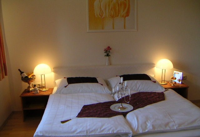 Außenansicht Weinpension Andrea, © Weinpension Adrea Sooss Gemütliches Schlafzimmer mit Doppelbett, Nachttischen und Lampen.