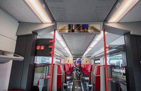 Zug, © Weinviertel Tourismus GmbH / Herbst Innenansicht eines modernen Zugwaggons mit roten Sitzen und digitaler Anzeigetafel.