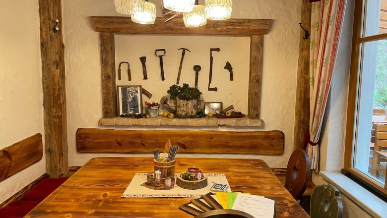 Gastzimmer, © KlammWirtin Rustikales Gastzimmer mit Holztisch, Wanddekoration aus alten Werkzeugen und gemütlicher Beleuchtung.