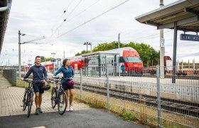 Bahnhof, © Weinviertel Tourismus GmbH / POV / Robert Herbst Zwei Personen mit Fahrrädern am Bahnhof Retz, im Hintergrund ein ÖBB-Zug.