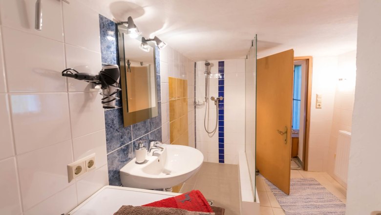 Bad und Dusche, © Wachahof Ein Badezimmer mit Waschbecken, Spiegel, Dusche und Handtüchern.