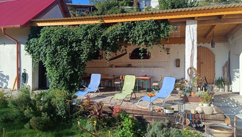 Pension Thayatalblick, © Riffer Gartenbereich mit Liegestühlen und überdachter Terrasse, umgeben von Pflanzen und Kletterpflanzen.