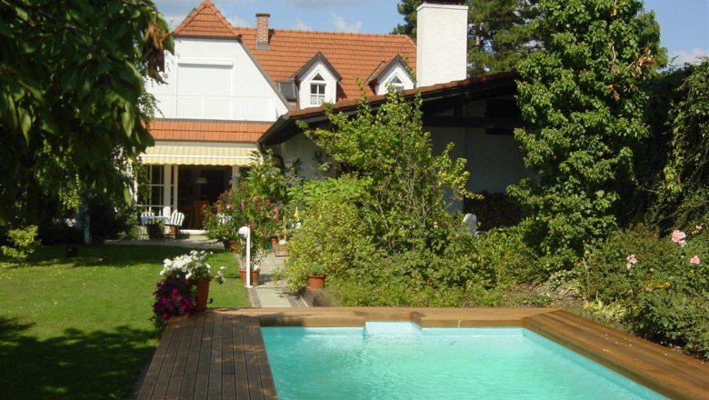 Pool, © Gästehaus am Steindl Ein Garten mit einem Pool, umgeben von Pflanzen und einem Haus im Hintergrund.