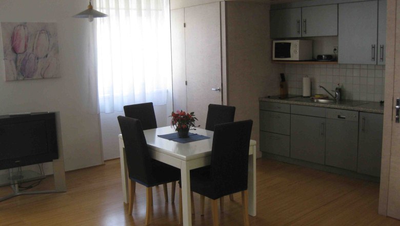 Küche, Apartment Gutmann, © Gutmann Graue Küchenzeile mit Esstisch und blauen Stühlen.