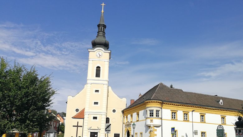 Pfarrkirche mit Pfarrhof, © Roman Zöchlinger Pfarrkirche mit Turm und angrenzendem Pfarrhof bei klarem Himmel.