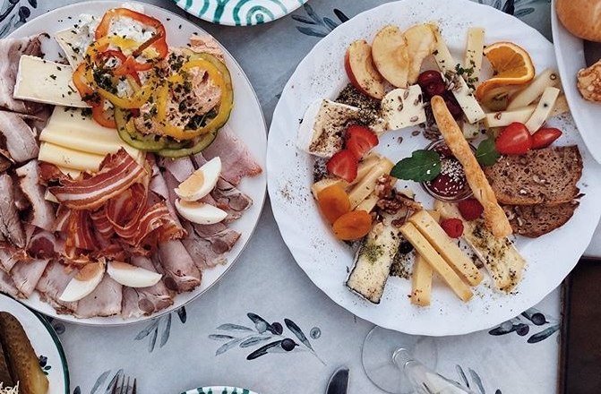 Winzerhof Hackner Heurigenjause, © Winzerhof Hackner Zwei Teller mit Aufschnitt, Käse, Gemüse und Obst auf einem Tisch.