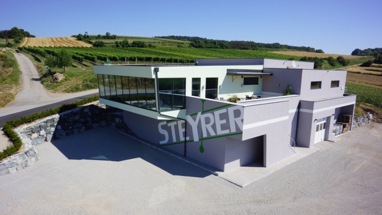 Weingut Steyrer, © Weingut Steyrer Modernes Weingut Steyrer mit Glasfassade und umliegenden Weinbergen.