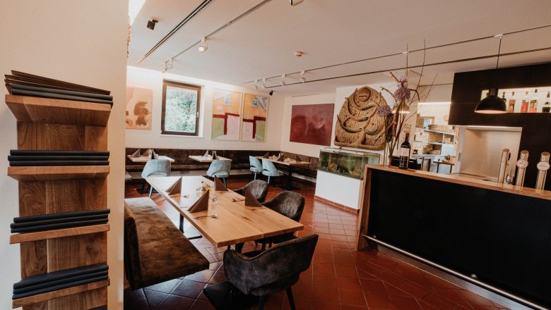 Der Löffler, © Nixxpixx.com Innenansicht eines modernen Restaurants mit Holztischen, blauen Stühlen und Kunstwerken an den Wänden.