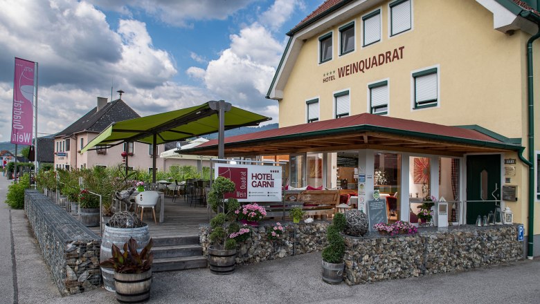 Terrasse Hotel Weinquadrat, © ivan-lukacic-photography Außenansicht des Hotels Weinquadrat mit Terrasse und grünen Sonnenschirmen.