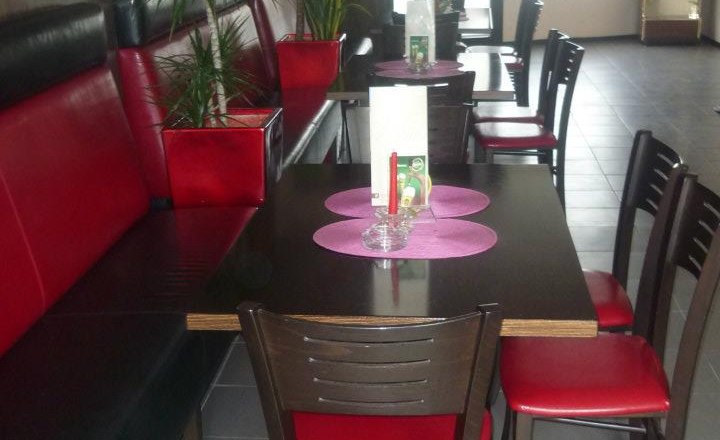 Café Bar Atlantis, Enzersdorf/Fischa, © Semir Koro Innenansicht eines Cafés mit roten und schwarzen Möbeln, Pflanzen und einem Dartautomaten.