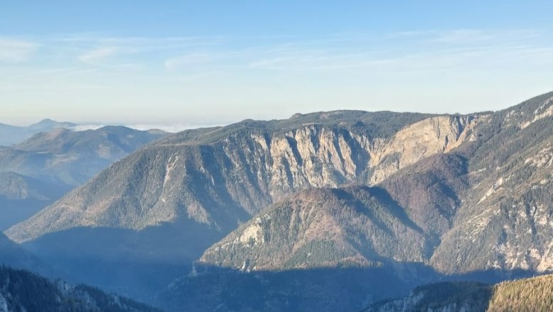 Höllentalaussicht, © Stefanie Gaulhofer Blick auf eine tiefe Schlucht mit steilen Felswänden und bewaldeten Bergen im Hintergrund unter klarem Himmel.