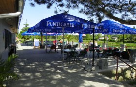 Gasthaus zum Silbersee, © Gasthaus zum Silbersee Außenbereich eines Gasthauses mit blauen Sonnenschirmen und Tischen.