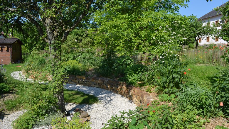 dsc_0062__monika_vesely, © Monika Vesely Ein grüner Garten mit Bäumen, Blumen und einem Kiesweg.