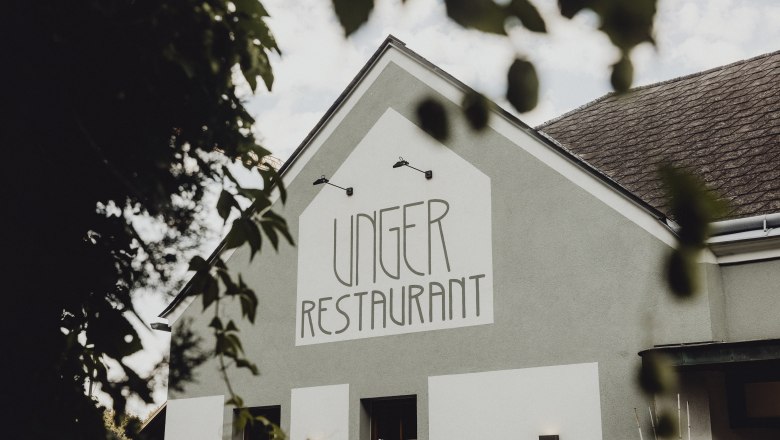 Gehobene Küche mit Vinothek in Pitten, © Niederösterreich Werbung/Sophie Menegaldo Außenansicht des Unger Restaurants mit grünem Gebäude und Schriftzug.