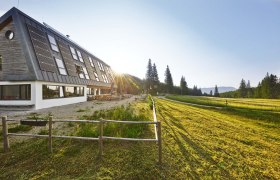 Naturfreundehaus Knofeleben am Gahns, © Wiener Alpen / Bene Croy Naturfreundehaus Knofeleben in einer sonnigen Berglandschaft mit Solarpaneelen auf dem Dach.