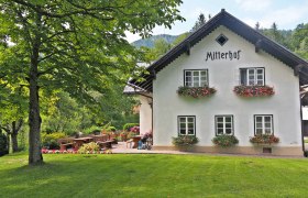 Bauernhof Mitterhof, © Mitterhof Ein traditionelles Bauernhaus mit dem Namen Mitterhof, umgeben von grüner Landschaft und Blumenbeeten.