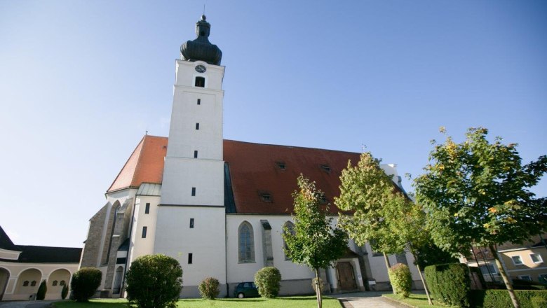 Wallfahrtskirche Mank, © schwarz-koenig.at Wallfahrtskirche Mank mit Turm und rotem Dach, umgeben von Bäumen und Rasenfläche.