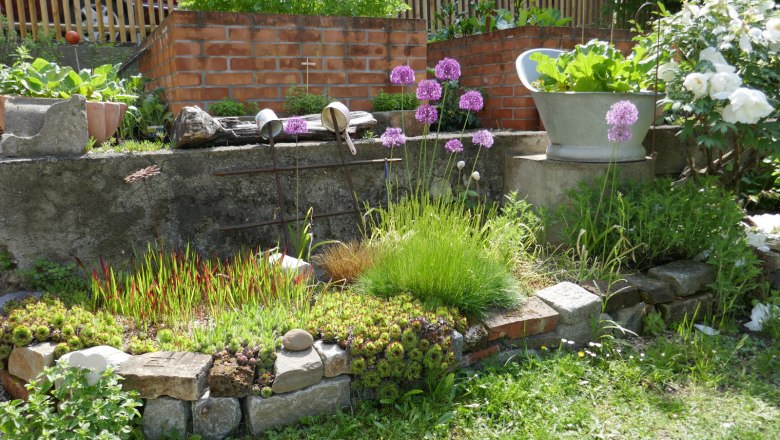 ijii7129, © Tina Perina Ein kleiner, gepflegter Garten mit Blumen, Kräutern und Ziegelmauern.