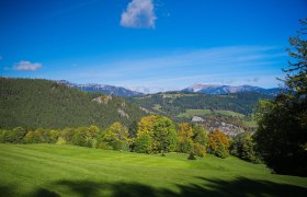 Schneebergblick Golfplatz Semmering, © Alexander Kramel Blick auf eine grüne Landschaft mit Hügeln und Bergen im Hintergrund, unter einem klaren blauen Himmel.