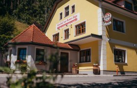 Gasthof in St. Oswald, © Niederösterreich Werbung/Daniela Führer Gelbes Gebäude mit der Aufschrift 'Gasthof zur Roten Säge' und einem Kaiser-Bierschild.