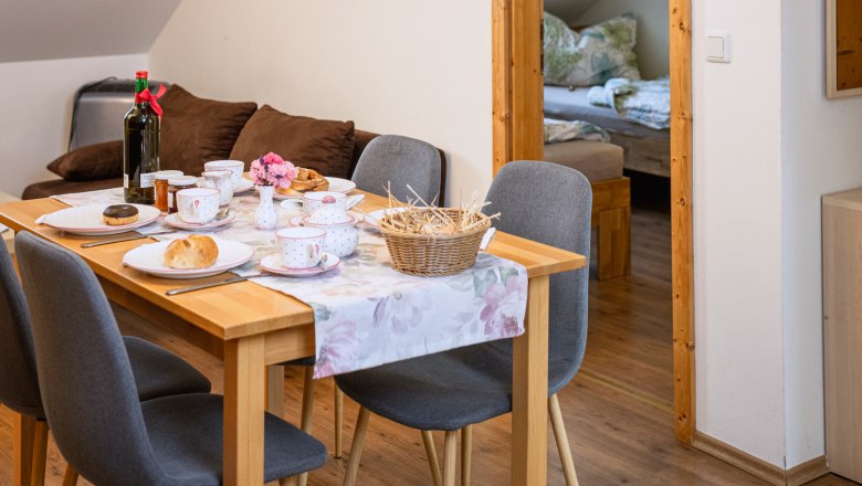 Am Arkadenhof, Ferienwohnung, © Martina Siebenhandl Essbereich in einer Ferienwohnung mit gedecktem Tisch und Blick ins Schlafzimmer.