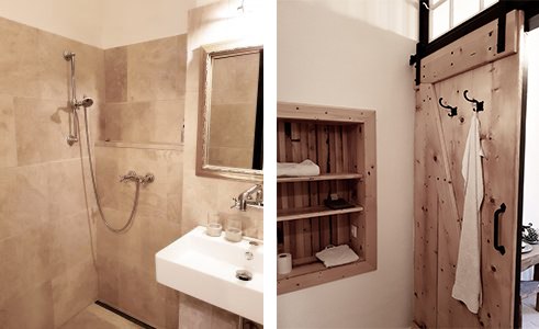 Badzimmer, © Gröger Ein Badezimmer mit einer Dusche, einem Waschbecken und einem Holzregal neben einer Schiebetür.