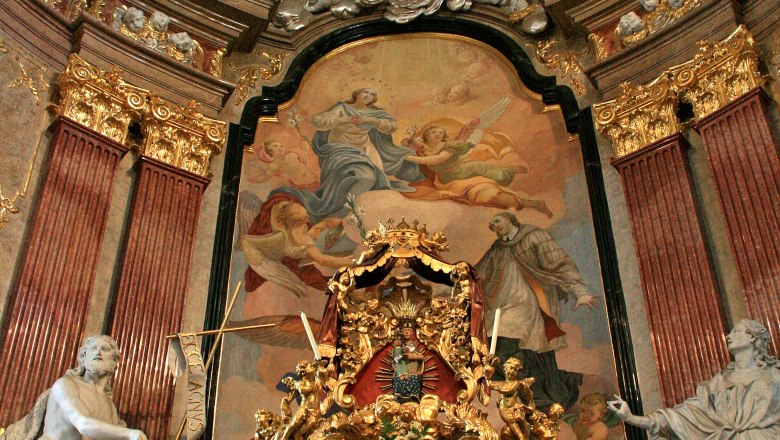 Minoritenkirche, © Stadtgemeinde Tulln Prunkvoller Altar in einer Kirche mit goldenen Verzierungen und religiösen Gemälden.