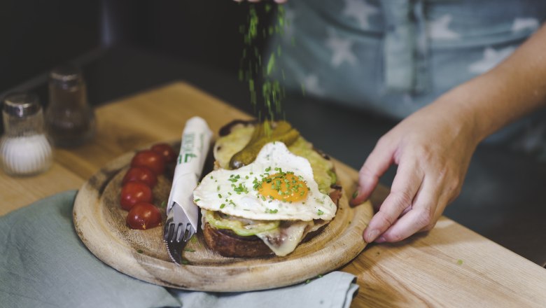 TDR-Speisen, © Buschenschank Buder Ein Teller mit einem belegten Brot, Spiegelei und Tomaten, garniert mit Schnittlauch.