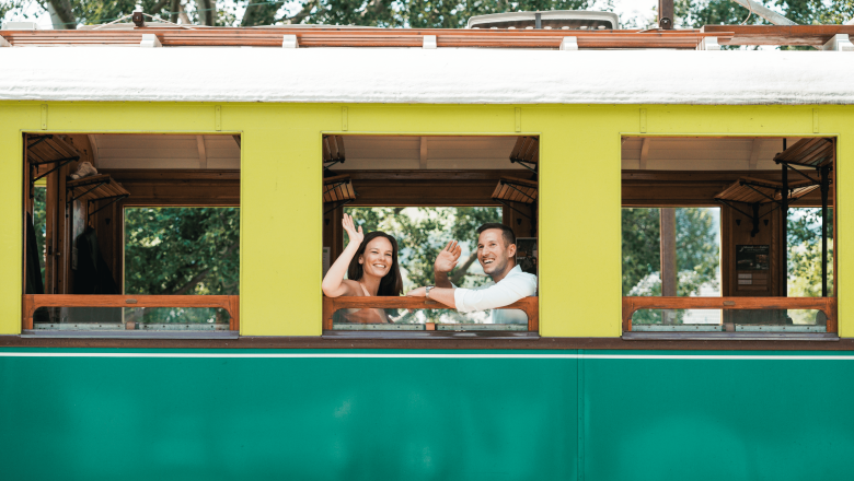 Höllentalbahn, © Österreich Werbung/Stefan Strasser Zwei Personen winken aus einem gelb-grünen Zugfenster.