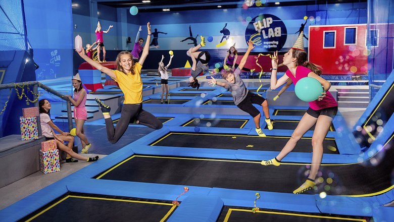 Flip Lab, © FLIP LAB GmbH & Co.KG/Nadine Studeny Photography Menschen springen auf Trampolinen in einer Halle mit dem Logo 'Flip Lab'.