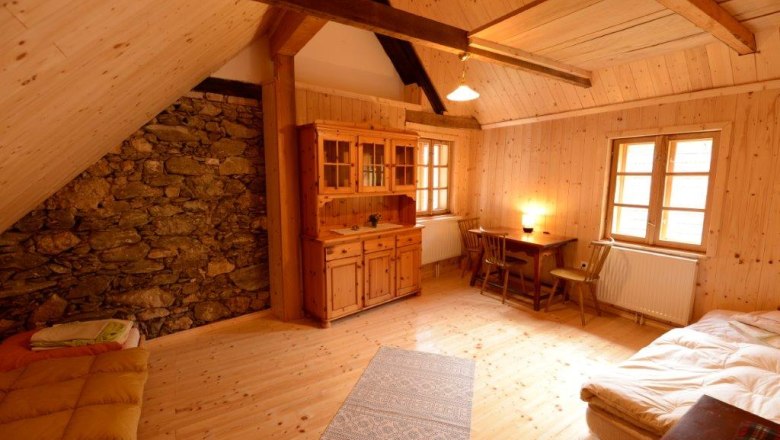 Zweibettzimmer Johanneshaus, © Martina Heilingsetzer Gemütliches Zimmer mit Holzwänden, zwei Betten, Tisch und Stühlen, Schrank und Steinwand.